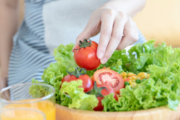 Close up shot of woman preparing salad or healthy meal in kitchen.