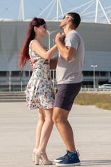 Young couple dancing Latino dance against urban landscape.