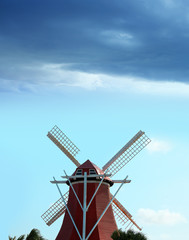 Traditional Netherlands culture of close up red wooden windmill over sunny blue sky