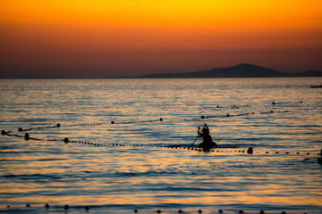People Silhouettes making water sports at sunset