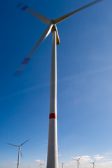 Windkraftanlage mit Langzeitbelichtung, leicht bewölkter blauer Himmel im Hintergrund