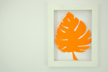 Flat lay orange paper monstrea palm leaf in a white plastic frame. Summer mockup
