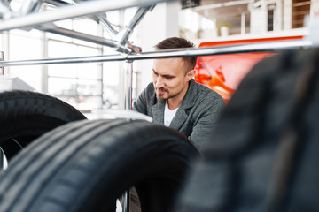 Fototapeta na wymiar Man choosing tyres for new car in showroom