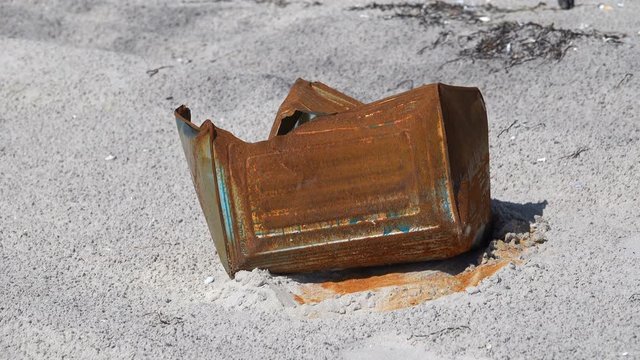 Rusty iron can on the sandy coast of the Black Sea
