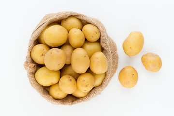 Sack of fresh raw potatoes on wooden background, top view