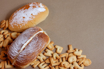 Cream-butter bread and ABC crackers on brown paper background.