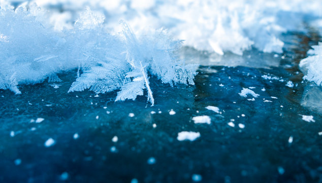 Winter ice background with snow and snowflakes. Natural texture of frozen water. New Year and Christmas card.