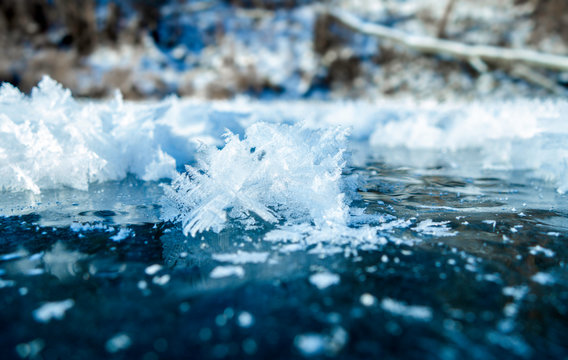 Winter ice background with snow and snowflakes. Natural texture of frozen water. New Year and Christmas card.