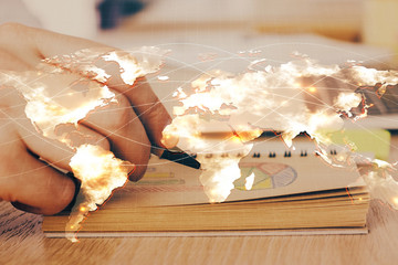 Double exposure of hands and notepad with business icons.