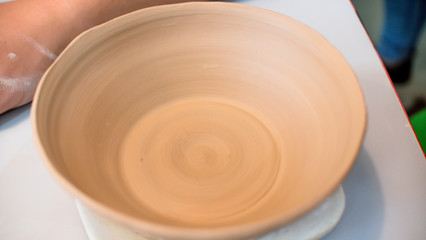 A raw clay pot in the hands of a potter. Workshop in the pottery workshop. Clay pot on a potter`s wheel