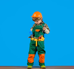 Little boy in helmet and tools. Kid as construction worker. Little boy plays construction worker. Builder. Little repairman. Child game. Tools for building. Little boy in builder's uniform with tools.