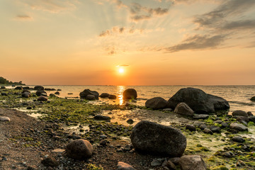 Fototapeta na wymiar Beautiful sunset at the beach of the baltic sea with boulders in the forground