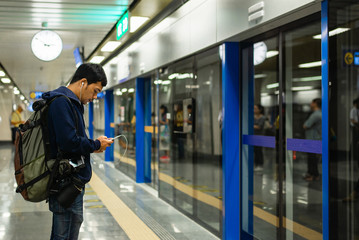 Exterior of moder Bangkok  metro with passengers on seats and young man  using their cell phones....