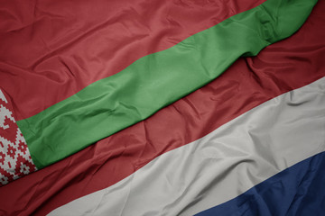 waving colorful flag of netherlands and national flag of belarus.