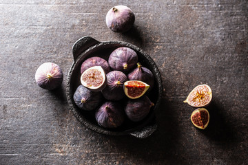 A few figs in a black bowl on an dark concrete table - Top of view