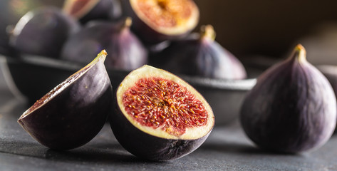 A few figs in a black bowl on an dark concrete table