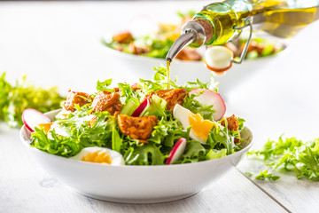 Salad with mixed ingredients pieces of chicken breast egg radish and olive oil