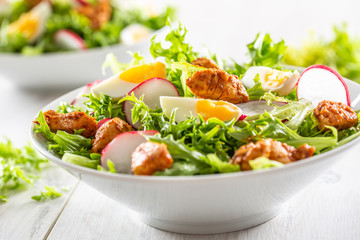 Salad with mixed ingredients pieces of chicken breast egg radish and olive oil