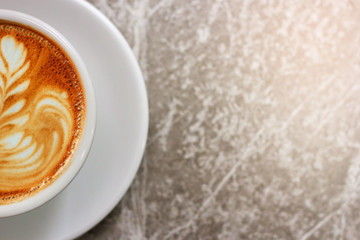 Top view. Closeup half of latte art coffee in white cup with blur pattern background
