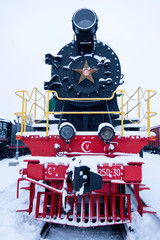 Steam train in the snow. Soviet black and red locomotive. Front view.