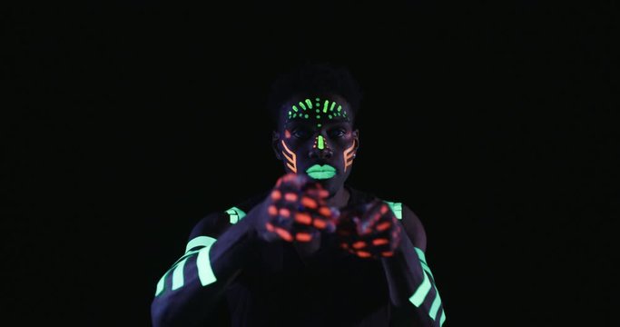 Studio, slow motion, close-up of a neon-painter dancing 