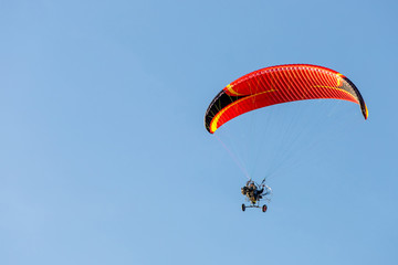 bright paraglider with a motor flies in the blue sky