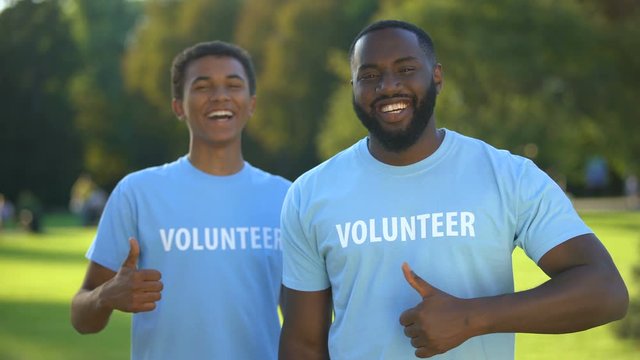 Positive afro-american males showing thumbs up, nature preservation volunteering