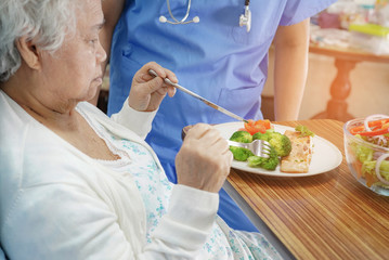 Asian senior or elderly old lady woman patient eating breakfast healthy food with hope and happy while sitting and hungry on bed in hospital..
