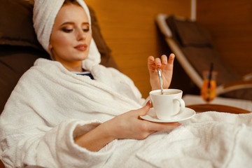 Sexy girl relaxing with cup of coffee in spa chair