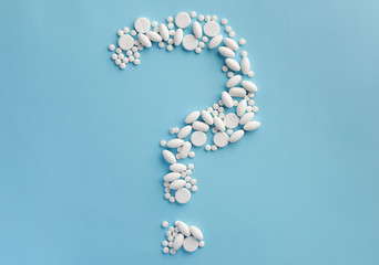 Question mark made by pills, isolated on blue background. Flat lay.