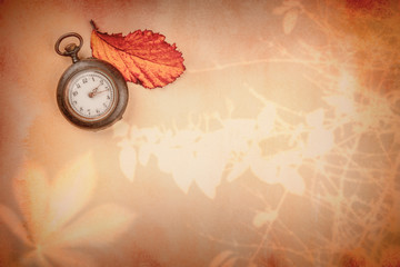 Nostalgic autumn design template. A vintage watch on old paper with organic plant shadows and a vibrant autumn leaf, with a place for text. Toned image