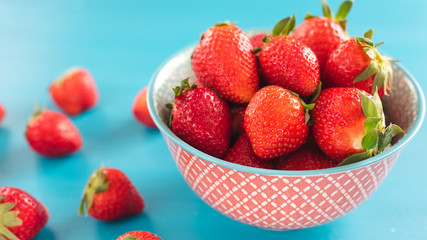bright printed bowl of fresh strawberries on blue wooden background