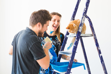 People, redecoration and renovation concept - portrait of couple with cat pour paint