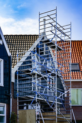 Scaffolding on a small brick house with wood paneling in Netherlands