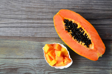 Fresh ripe organic papaya tropical fruit cut in half and sliced on old wooden background.Healthy eating,diet or vegan food concept.Copy space.Selective focus.