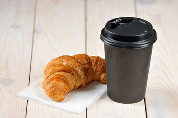 Coffee in a paper cup and a croissant. Takeaway food and drink concept. Free space for text. Light...