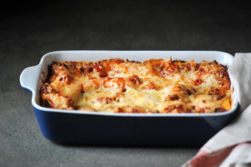 A dish of lasagna. Close-up. Dark background.