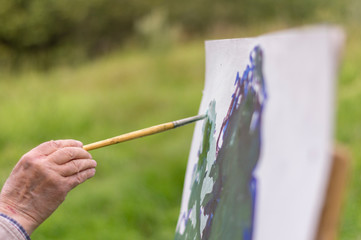 Drawing oil paintings of a natural landscape on a white cardboard