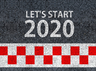 happy new year 2020. lets start 2020 and racing start line written on an asphalt road