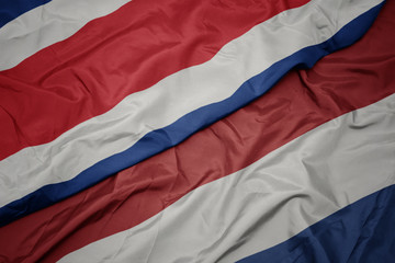waving colorful flag of netherlands and national flag of costa rica.