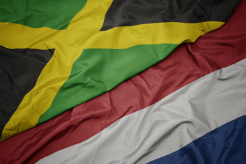 waving colorful flag of netherlands and national flag of jamaica.