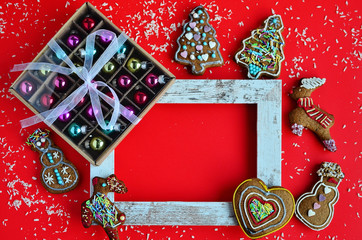 Rad color as a background on the christmas card with decoration, gift and gingerbreads. Wooden frame with mock up. Flatlay.