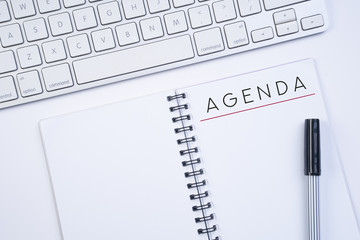 Business agenda, planning concept. Spiral notebook with Agenda text on white background. Flat lay or top view.