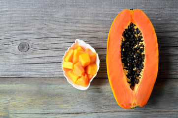 Fresh ripe organic papaya tropical fruit cut in half and sliced on old wooden background.Healthy eating,diet or vegan food concept.Copy space.Selective focus.