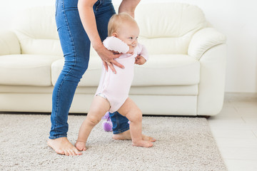 Little baby girl first steps with the help of mom