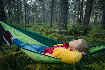 Woman resting in hammock outdoors. Sleeping outdoors.