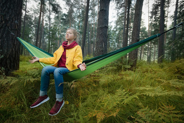 Woman resting in hammock outdoors. Meditation outdoors.