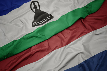 waving colorful flag of netherlands and national flag of lesotho.