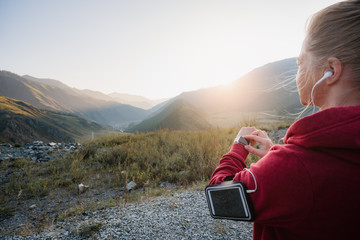 Sportswoman with smart watch taking a break outdoors at the top of the mountain.