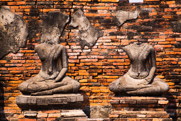 View on isolated ancient headless busts in front a red brick wall -  Ayutthaya, Thailand